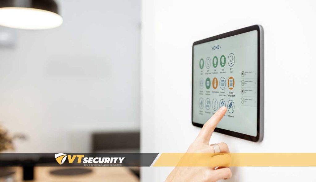 Smart home automation control panel with finger touching screen, showcasing integrated security and energy management features, branded with VT Security logo.